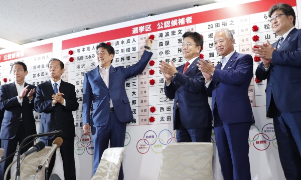 아베 신조 일본 총리가 지난 21일 자민당본부 개표센터에서 당선자 이름에 장미꽃을 붙이고 있다. / 사진=연합뉴스