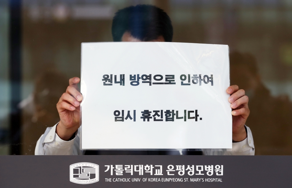 21일 오전 환자이송요원 중 1명이 신종코로나바이러스 감염증(코로나19) 1차 양성 판정을 받은 서울 은평성모병원에서 관계자가 휴진 안내문을 붙이고 있다. / 사진=연합뉴스