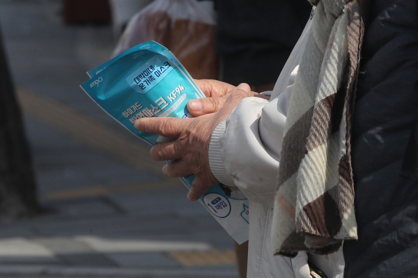 21일 오전 서울 종로구의 한 약국 앞에서 시민이 구입한 마스크를 손에 들고 있다. / 사진=연합뉴스