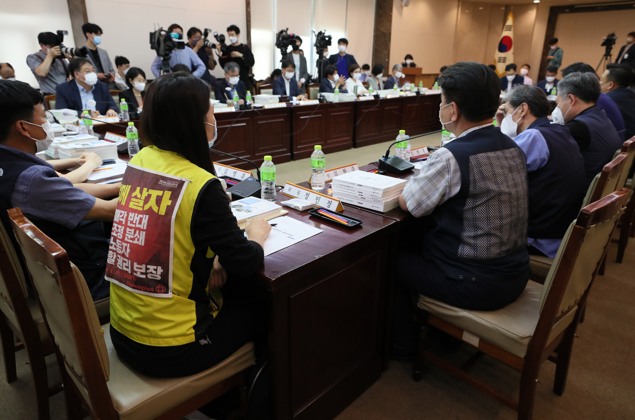 지난 1일 정부서울청사에서 열린 제4차 최저임금위원회 전원회의에서 정민정 마트산업노조 사무처장(앞줄 왼쪽 두 번째)이 ‘함께 살자’ 글귀가 적힌 현수막을 옷에 부착한 채 회의에 참가하고 있다. / 사진=연합뉴스