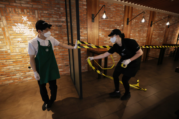 수도권 프렌차이즈 커피 전문점 매장 내 이용이 금지된 30일 오후 서울 중구 스타벅스 한국프레스센터점에서 직원들이 좌석 이용 통제선을 설치하고 있다. /사진=연합뉴스