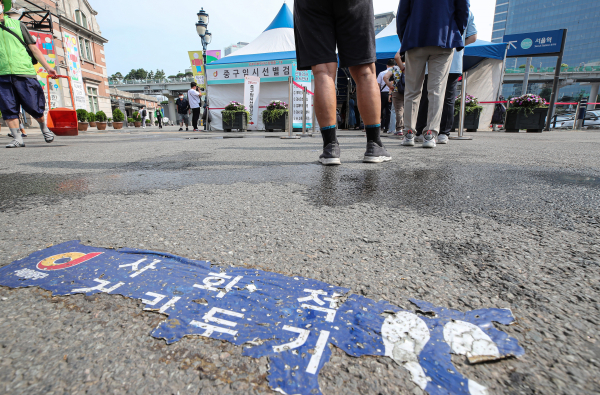 6일 서울 중구 서울역에 마련된 코로나19 선별검사소에 진단 검사를 받으려는 시민들 행렬 아래 낡아버린 사회적 거리두기 안내 스티커가 붙어 있다. / 사진=연합뉴스