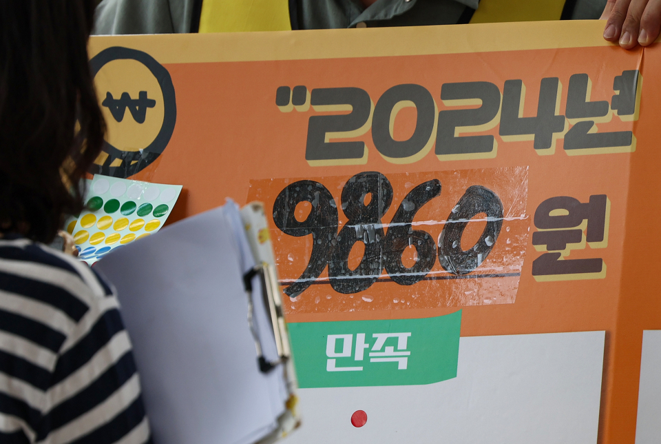 지난 19일 오후 서울 종로구 마로니에공원에서 한 시민이 이날 오전 결정된 최저임금에 관한 의견을 묻는 스티커 설문에 참여하고 있다./ 사진=연합뉴
