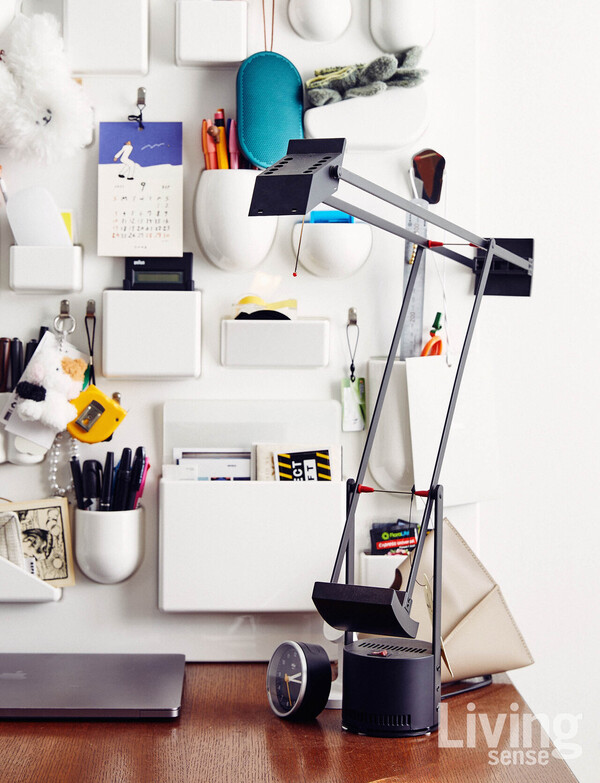 책상에 아르떼미데artemide.com 스탠드 조명과 비트라의 유텐실로가 놓여 있다.