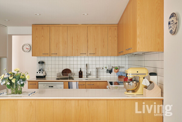 내추럴한 밝은 우드톤으로 연출한 주방. 상부장에 무늬목 시트지를 위아래 다른 방향으로 붙여 자연스러운 나뭇결을 살린 것이 포인트 