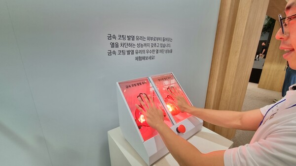 금속 코팅 발열 유리(왼쪽)와 텅스텐 유리의 열 차단 성능을 체험하고 있다.  텅스텐 유리의 온도는 금방 손을 떼고 싶을 만큼 뜨거워졌지만 금속 코팅 발열 유리에서는 손을 계속 댈 수 있을 정도의 온기가 느껴졌다. / 사진=최동훈 기자