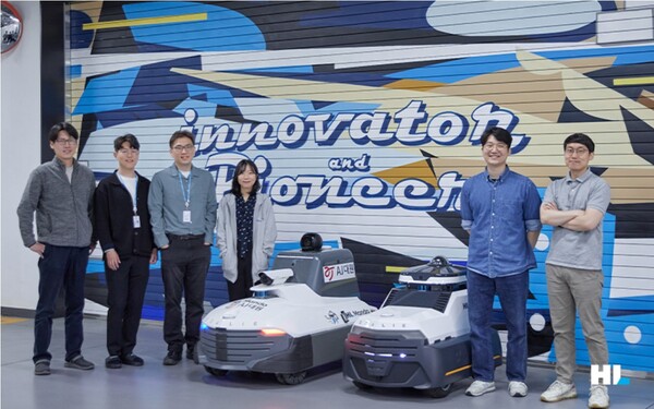 순찰로봇 골리(Goalie)를 개발한 HL만도 직원들이 로봇 옆에서 기념촬영하고 있다. / 사진=HL만도