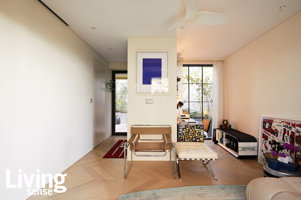 부부가 책을 읽거나 영화를 보며 취미생활을 누리는 1층의 거실. 셰브런패턴의 원목마루와 십자 모양 창호를적용해 이국적인 느낌을 자아냈다.