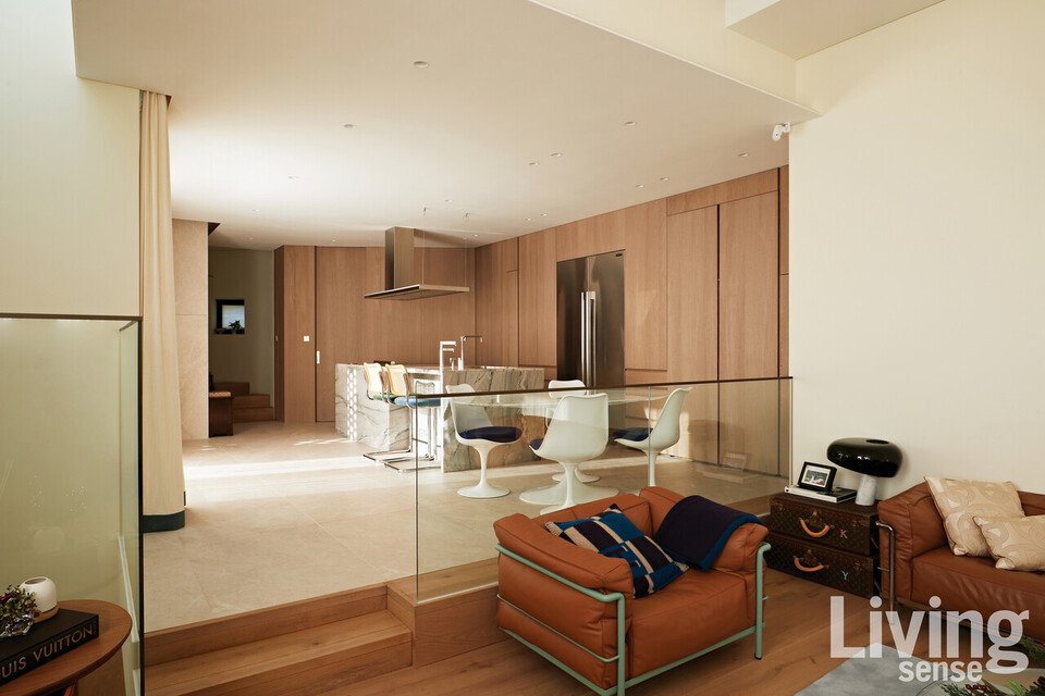 웜 화이트 톤으로 온화한 감성이 흐르는 거실과 주방. 두 공간 사이에 단차를 두어 연결되어 있음에도 분리감을 형성했다.