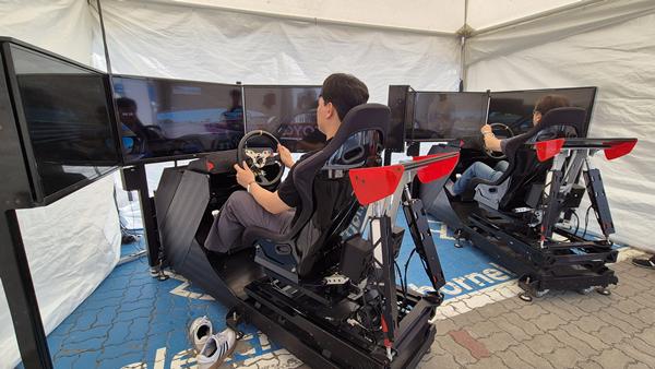 취재진들이 BMW 드라이빙 센터 주차공간에 마련된 조종 시뮬레이터를 체험하고 있다. / 사진=최동훈 기자