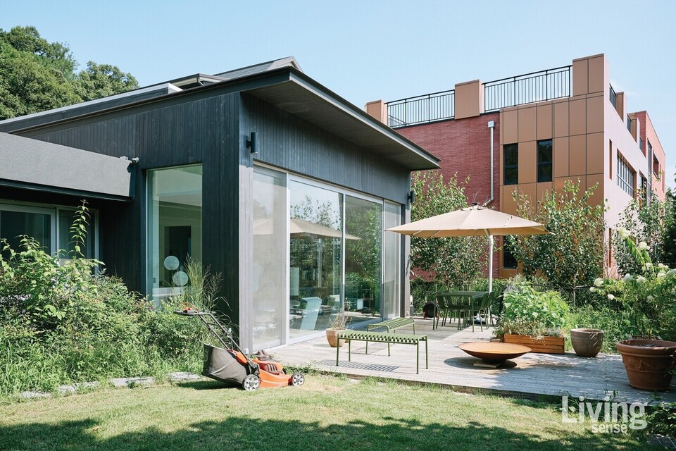 검은 외장재와 유리 파사드가 대비를 이루며 정원을 품는다. 창을 열면 실내의 공기와 바깥의 바람이 스며들고, 마당은 식사와 휴식, 아이의 놀이까지 아우르는 다층의 무대로 변한다.