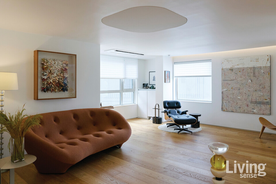 따뜻한 테라코타 컬러의 리네로제Ligne Roset쁠룸PLOUM 소파는 디사모빌리에서 구매한 것. 소파 위에 건 전광영 작가의 작품, 거실 정면에 배치한 홍정우 작가의 회화가 거실을 한층 따뜻한 분위기로 만든다.